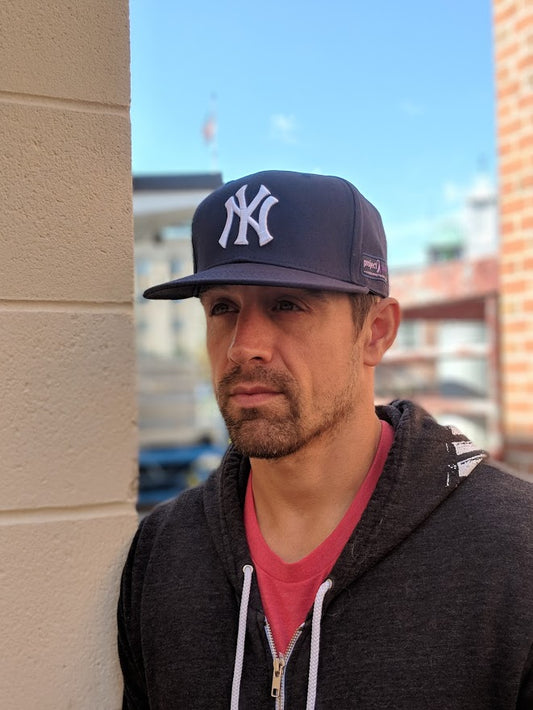 Man wearing Yankee Hat with Project Purple logo on the side