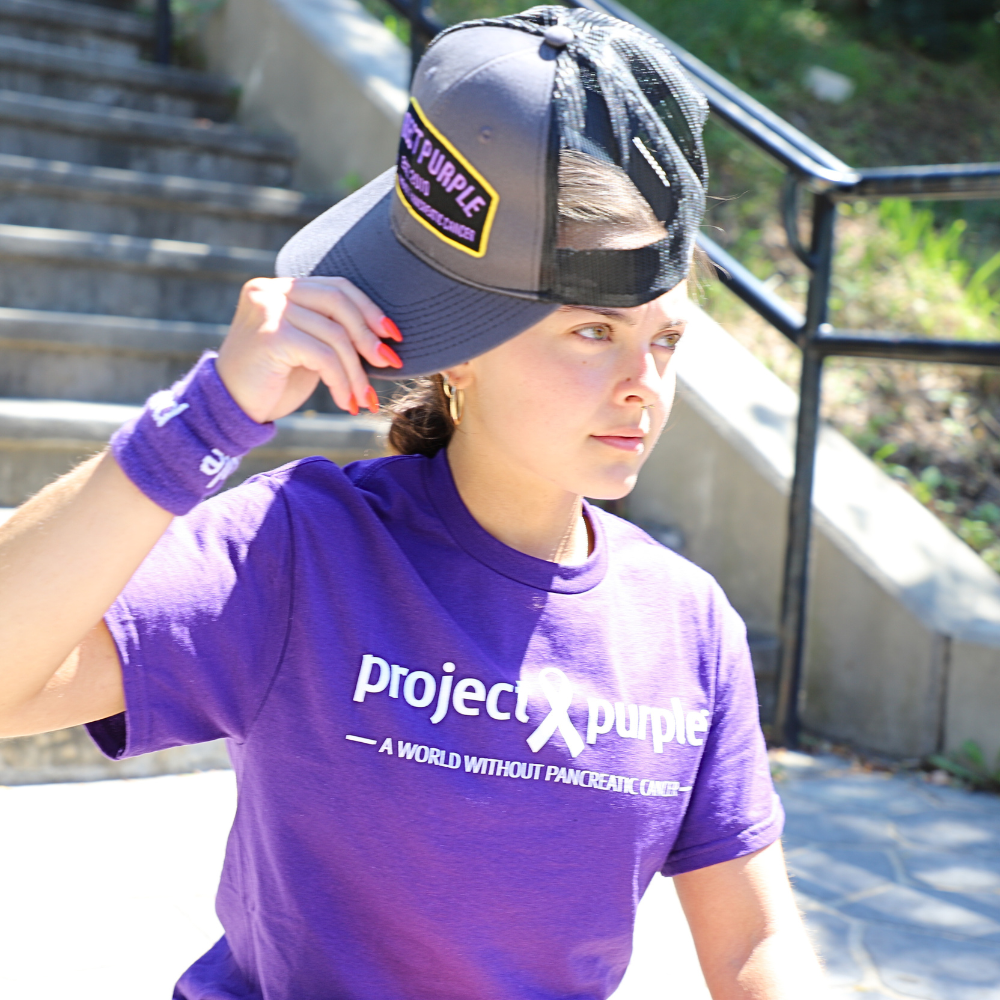 girl taking off black hat wearing purple shirt