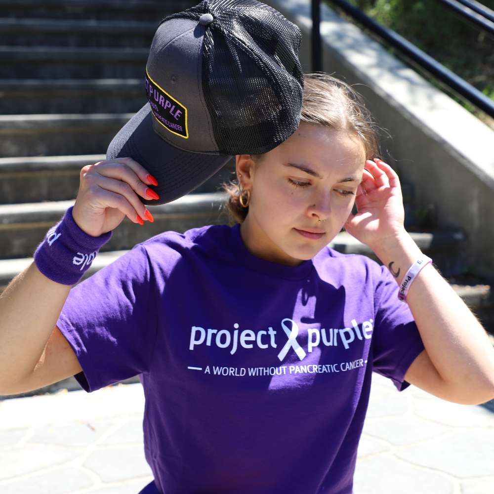 girl taking off hat in purple shirt